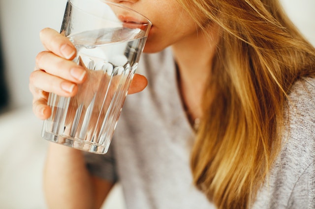 woman drinking water out of a glass